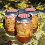Homemade apple pie filling in pint jars surrounded by leaves